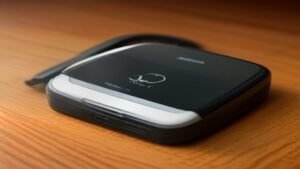 Robô aspirador de cabeça para baixo com a tampa do compartimento da bateria aberta sobre uma mesa de madeira.