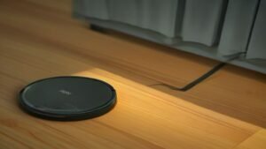 Pessoa utilizando um smartphone para configurar o robô aspirador KaBuM K100 através de um aplicativo em uma sala de estar iluminada.